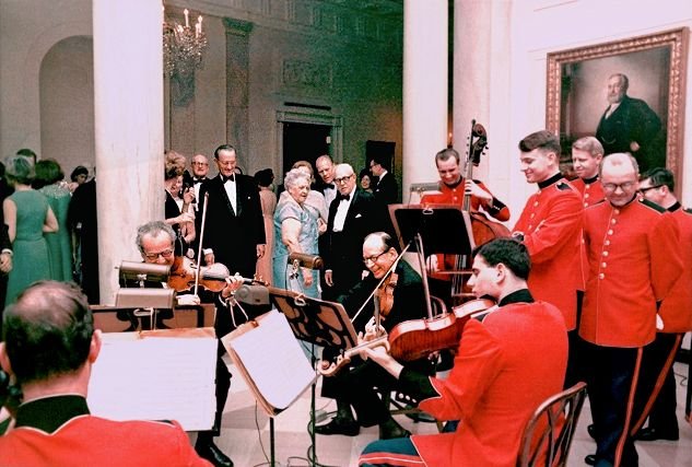 When Fortas resigned in May 1969, newspapers printed this photo taken in the foyer of the White House with LBJ, George Meany, Gerald Ford, and the rest of the Marine Strings watching quartets played by (from left) Daniel Rothmuller (back to camera, cello), Budapest String Quartets violinist Alexander Schneider (seated, first violin), Abe Fortas (seated, second violin), Dave Wundrow (standing, bass, making this technically a string quintet) and Alan de Veritch (seated, viola). Photo taken January 25th, 1968.